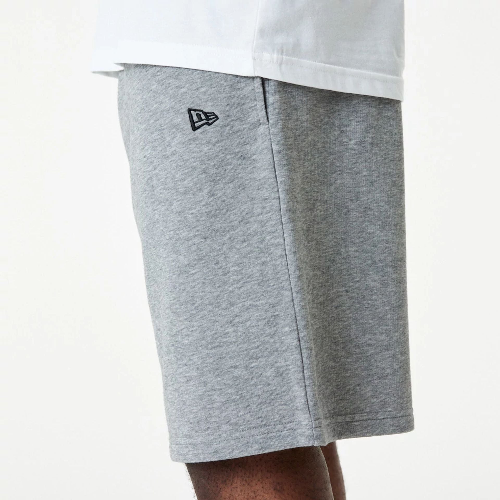 The Male model is wearing New Era Essential Grey Shorts 4