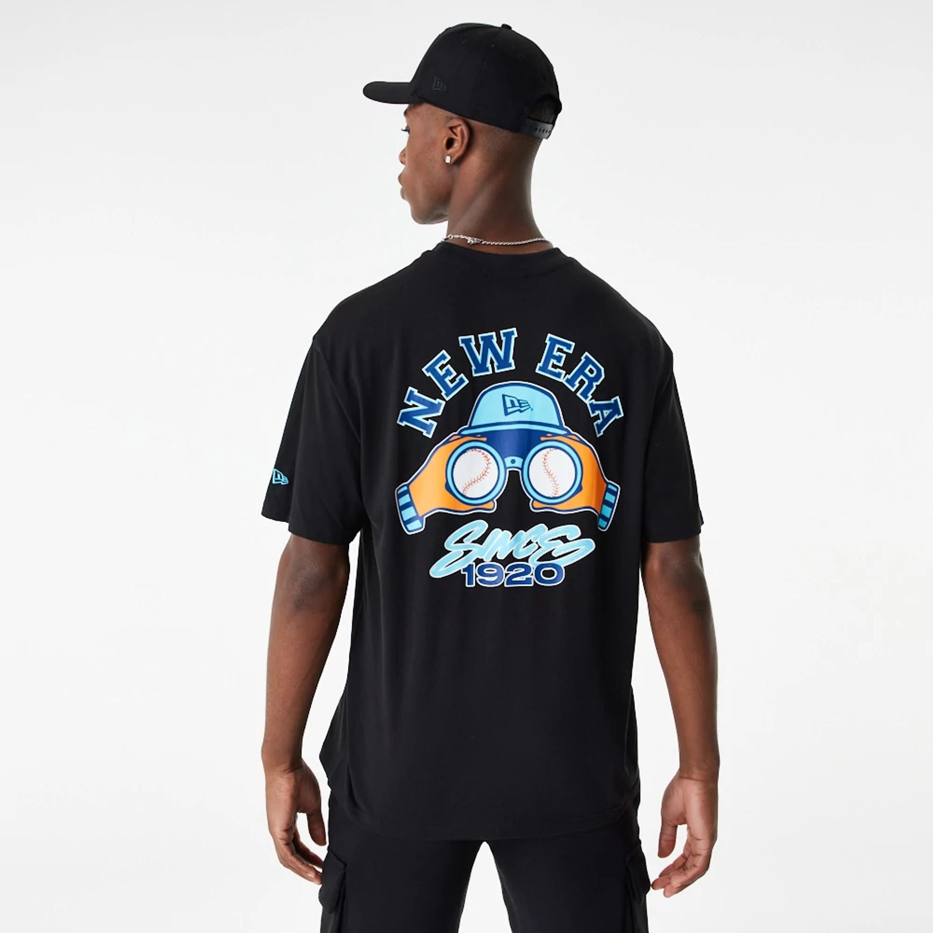 The Male model is wearing New Era Baseball Binoculars Graphic Black Oversized T-Shirt 1