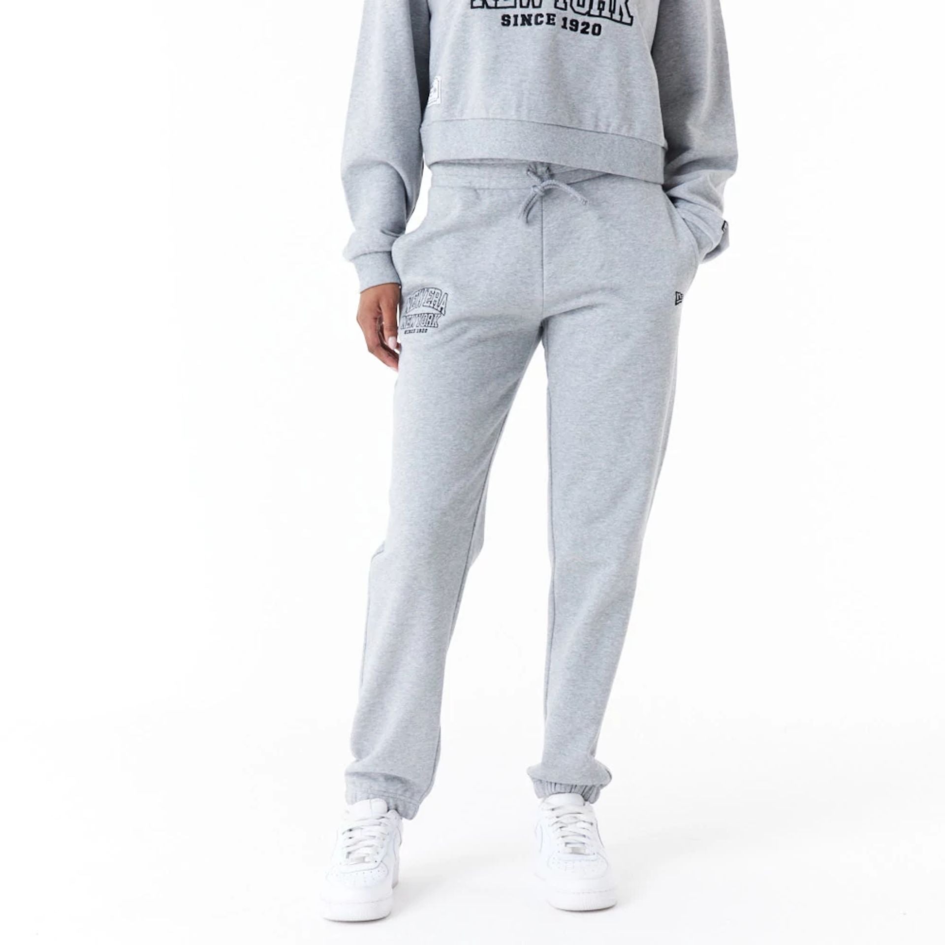 The Female model is wearing New Era Womens Arch Wordmark Grey Joggers 1