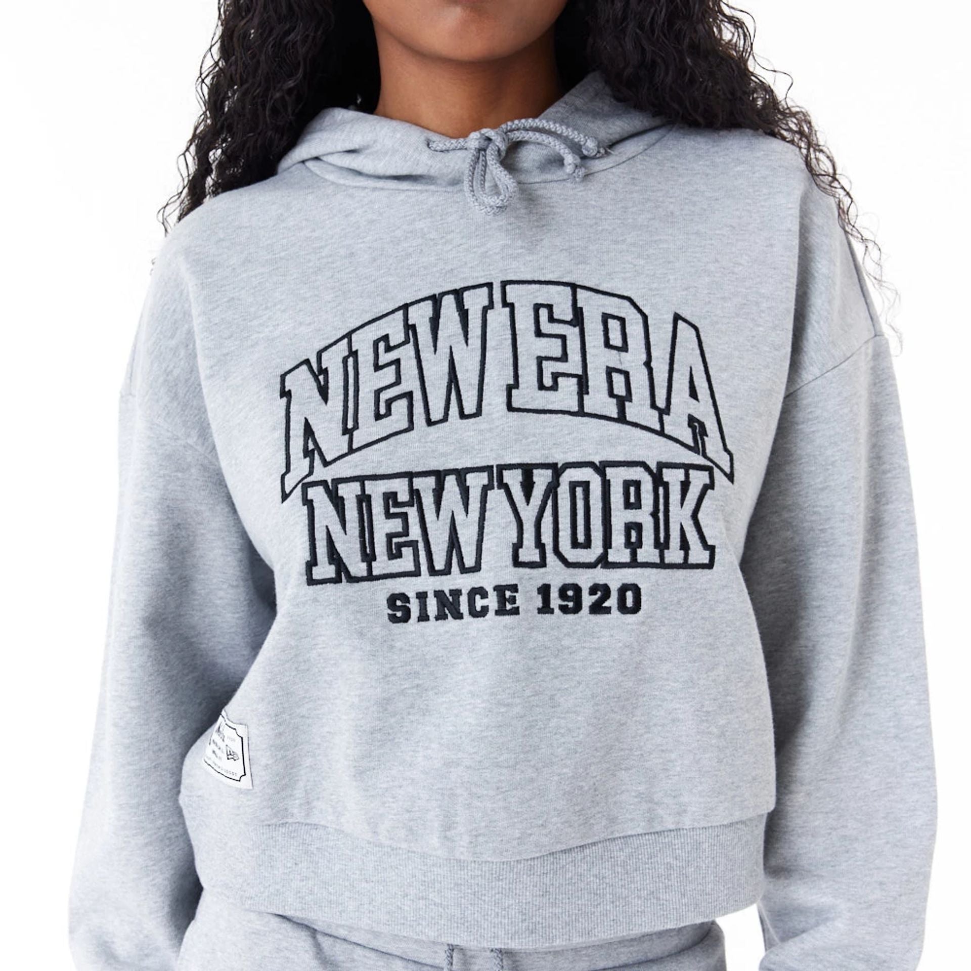 The Female model is wearing New Era Womens Arch Wordmark Grey Crop Pullover Hoodie 5