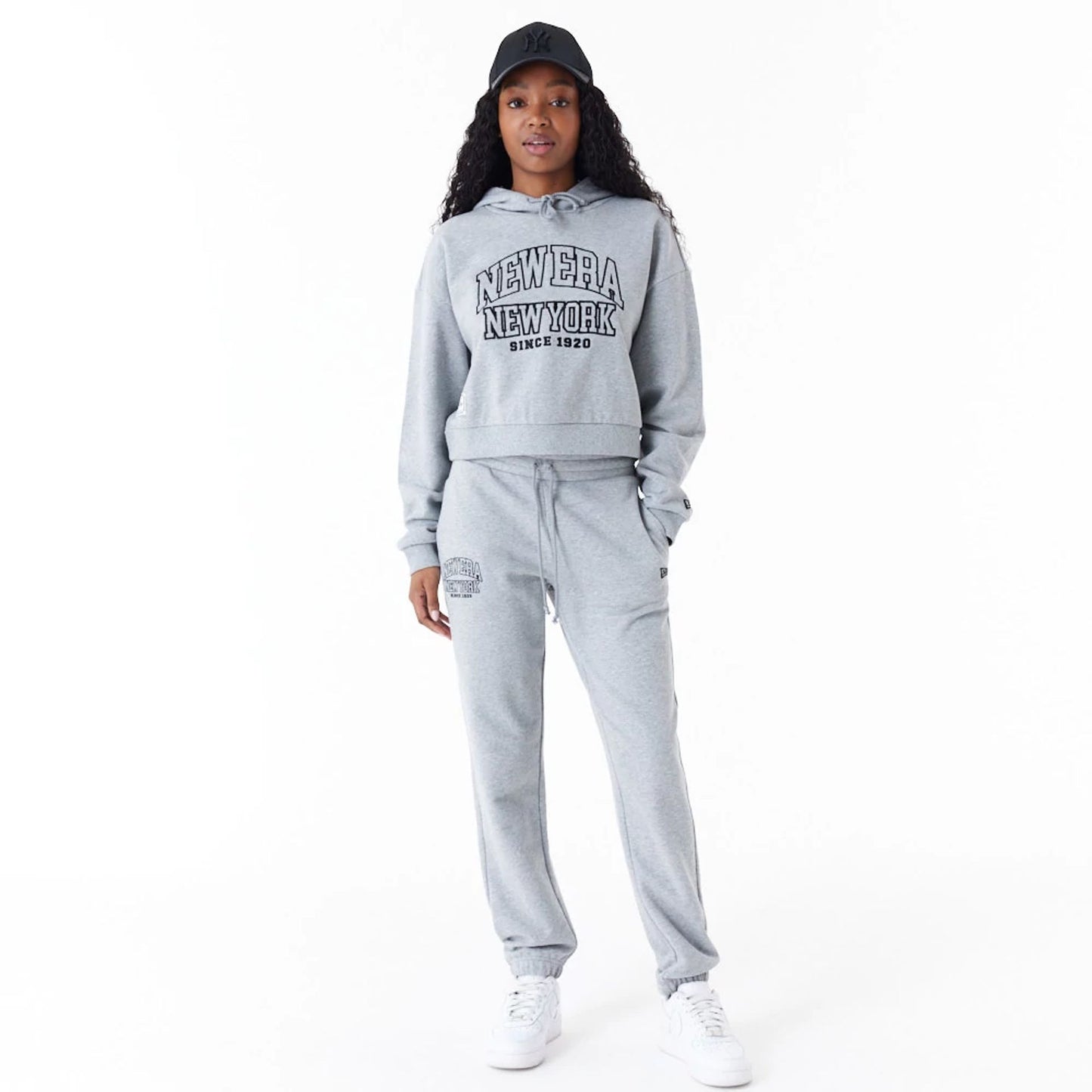 The Female model is wearing New Era Womens Arch Wordmark Grey Crop Pullover Hoodie 4