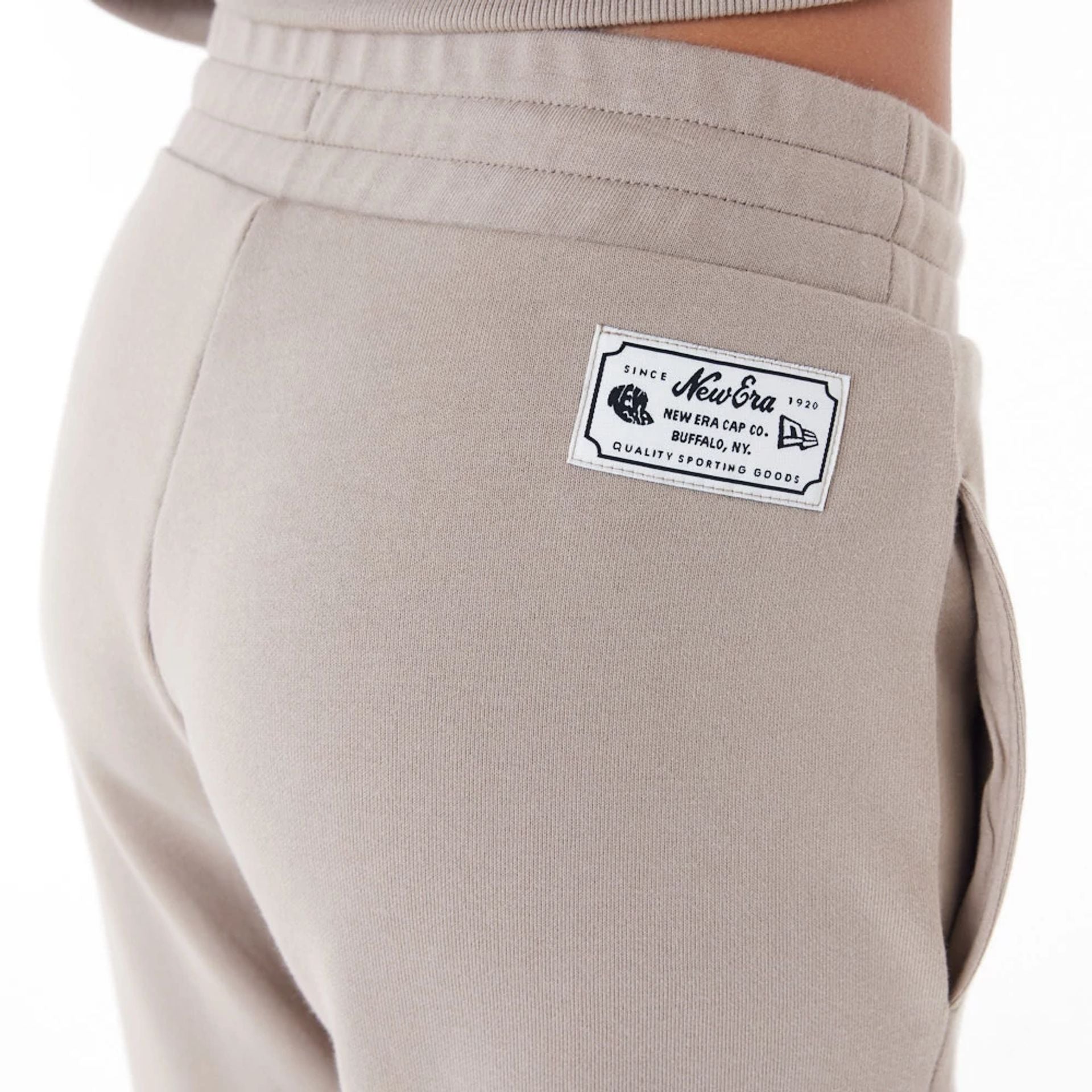 The Female model is wearing New Era Womens Arch Wordmark Brown Joggers 9