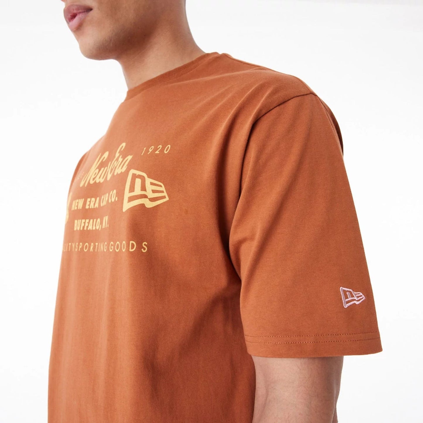 The Male model is wearing New Era Heritage Patch Brown Oversized T-Shirt 6