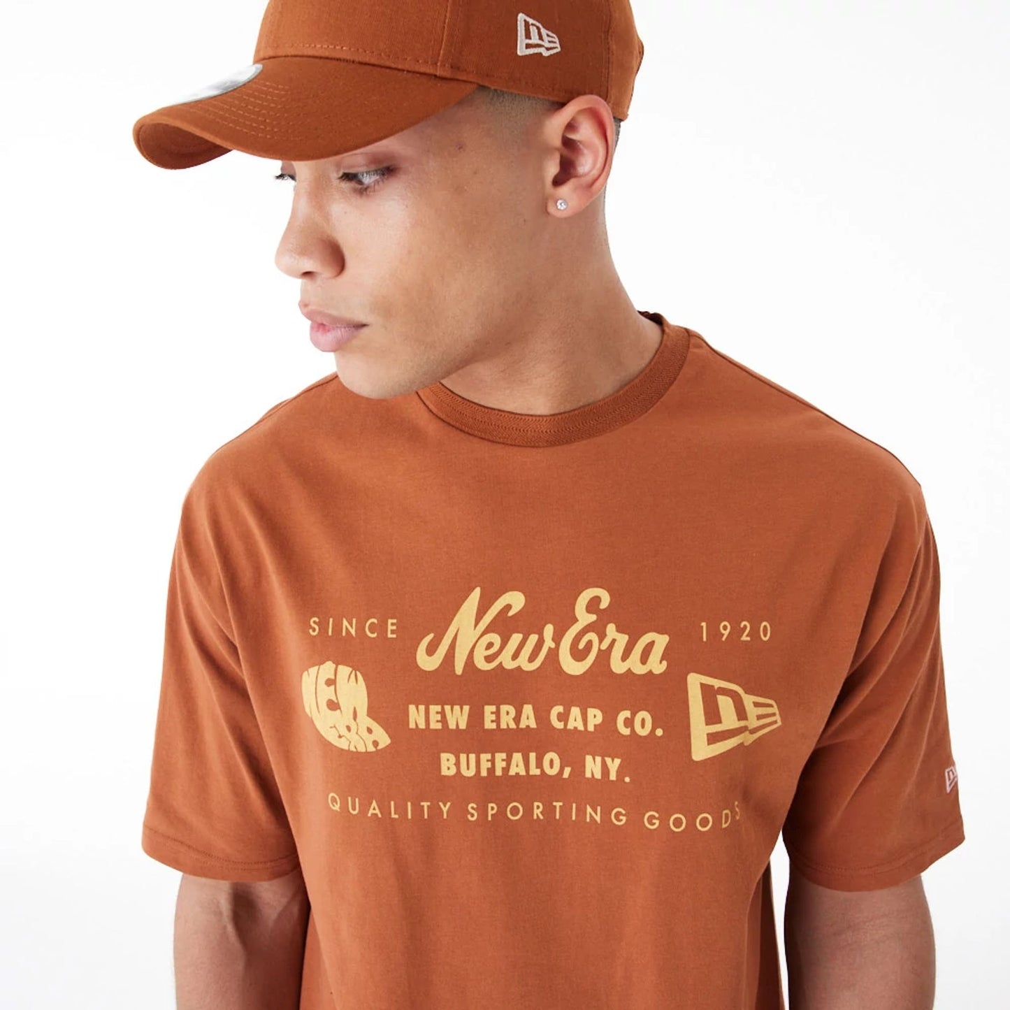 The Male model is wearing New Era Heritage Patch Brown Oversized T-Shirt 1