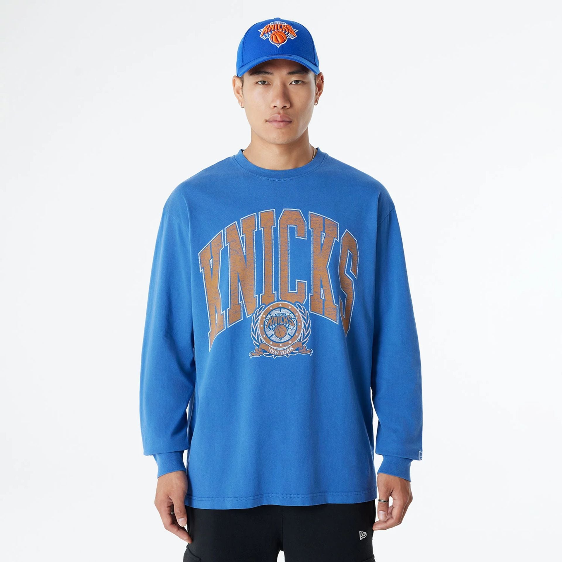 The Male model is wearing New York Knicks Oversized Essential Blue Oversized Long Sleeve T-Shirt 1