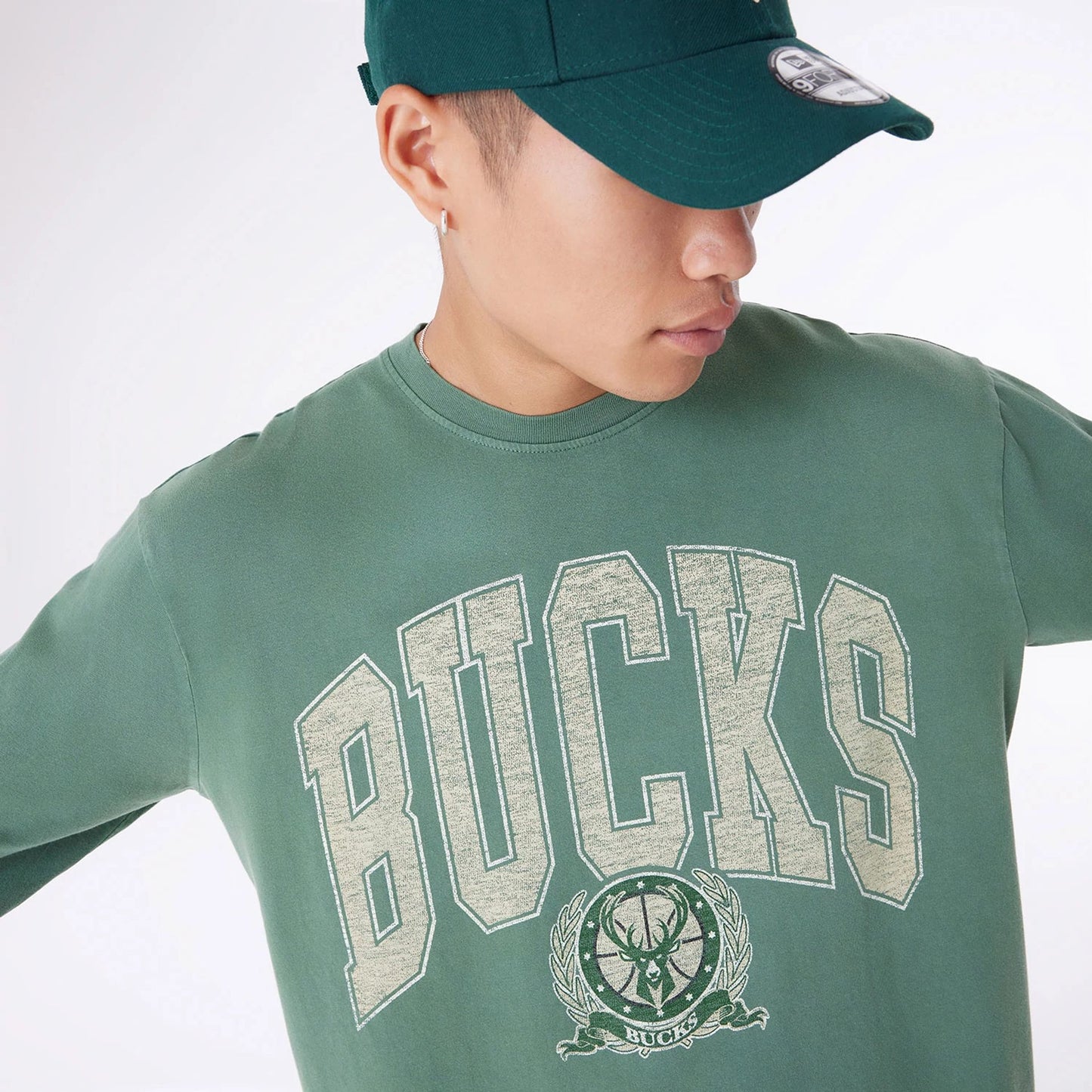 The Male model is wearing Milwaukee Bucks Oversized Essential Dark Green Oversized Long Sleeve T-Shirt 5