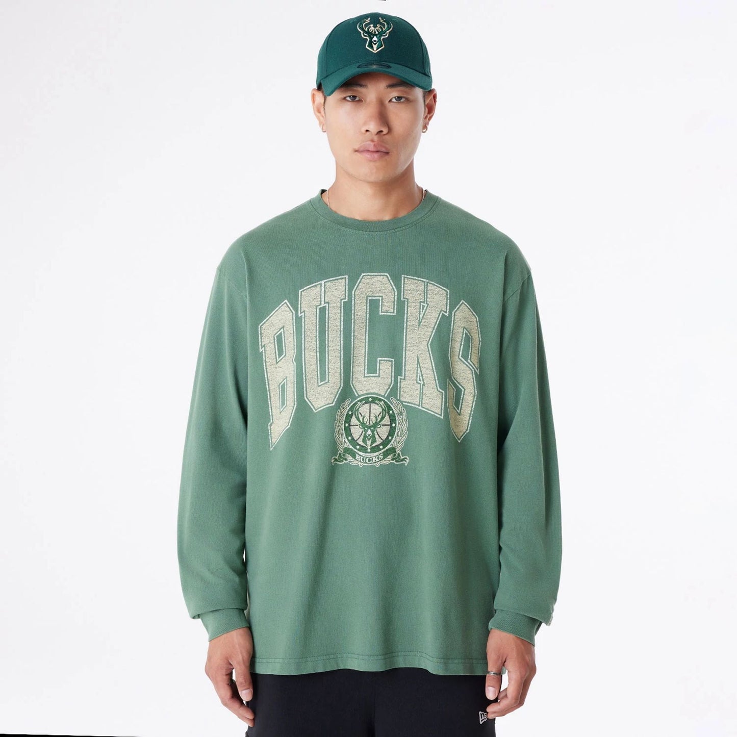 The Male model is wearing Milwaukee Bucks Oversized Essential Dark Green Oversized Long Sleeve T-Shirt 1