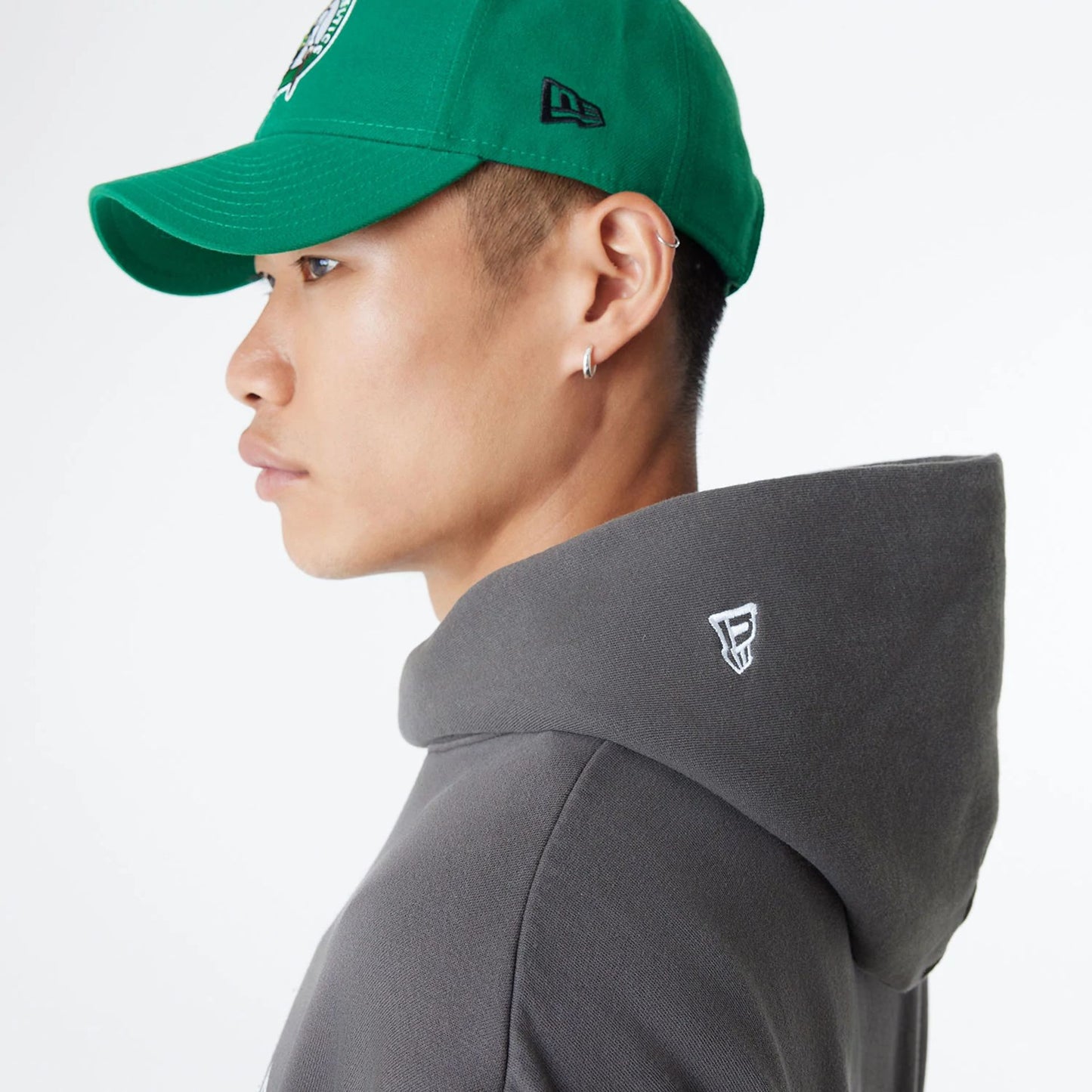 The Male model is wearing Boston Celtics Oversized Essential Dark Grey Oversized Pullover Hoodie 6