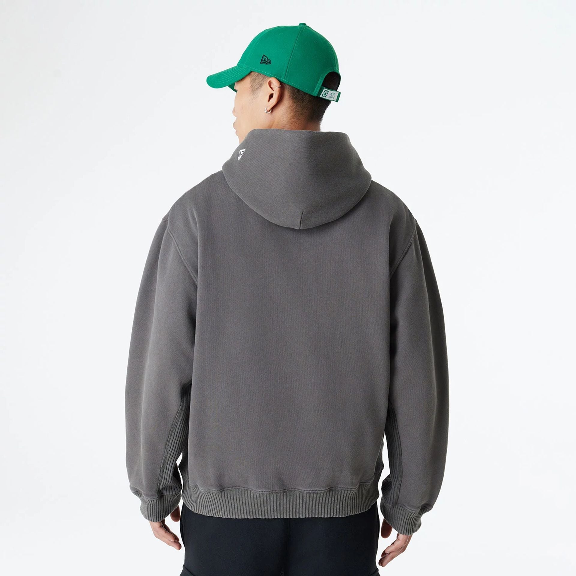 The Male model is wearing Boston Celtics Oversized Essential Dark Grey Oversized Pullover Hoodie 2