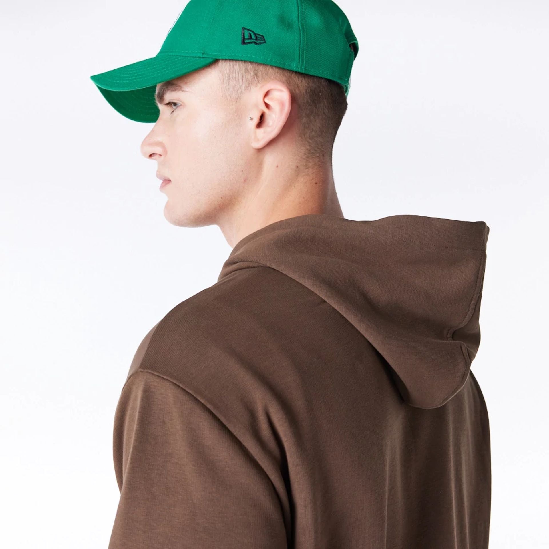 The Male model is wearing Boston Celtics League Essential Dark Brown Oversized Pullover Hoodie  6