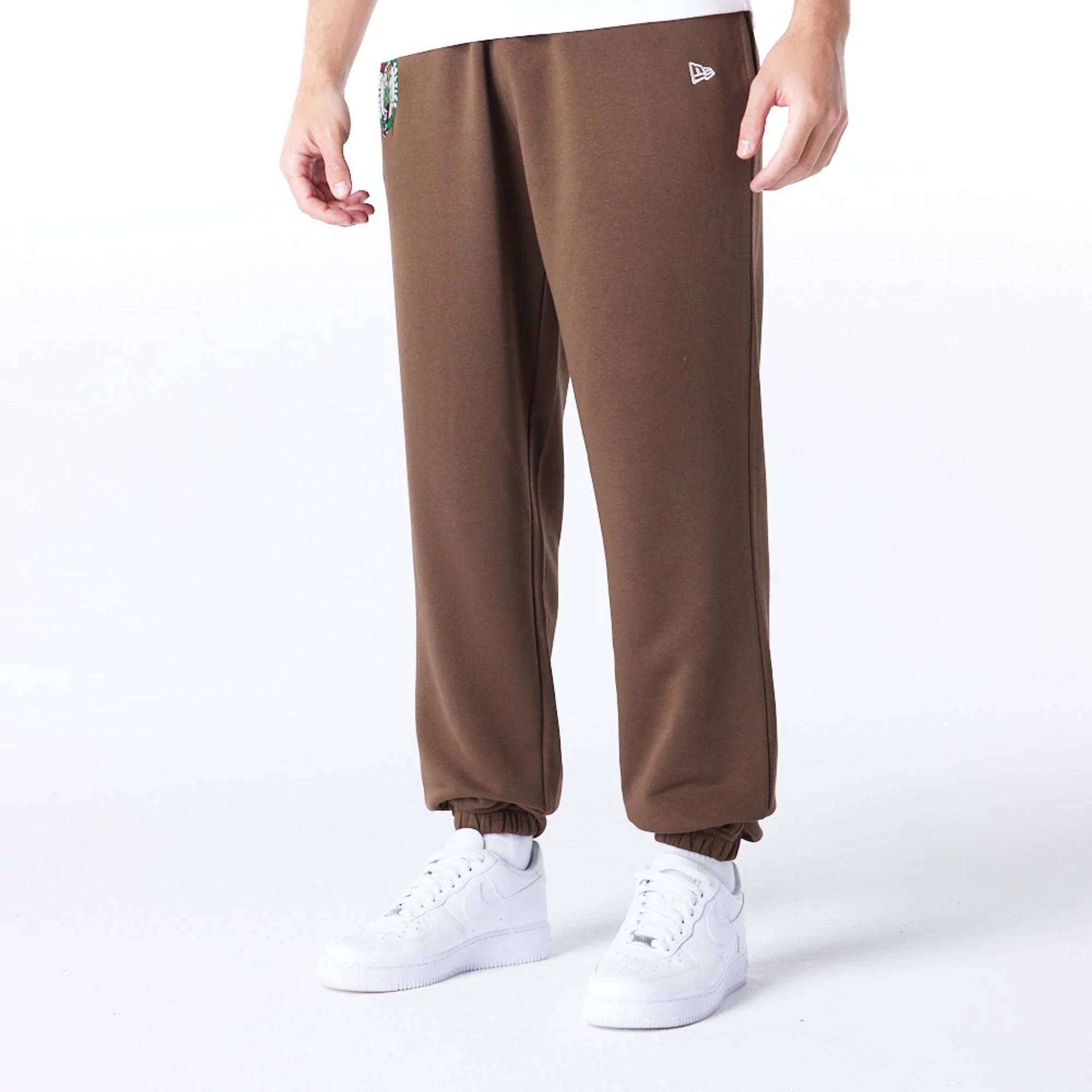 The Male model is wearing Boston Celtics League Essential Dark Brown Track Joggers  1