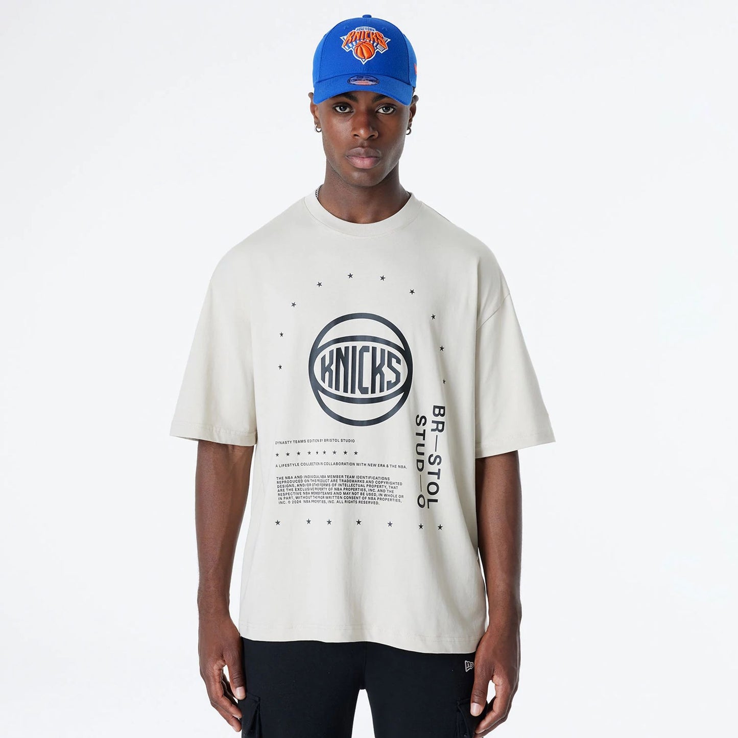 The Male model is wearing New York Knicks Bristol Studio x NBA Light Beige Oversized T-Shirt 1