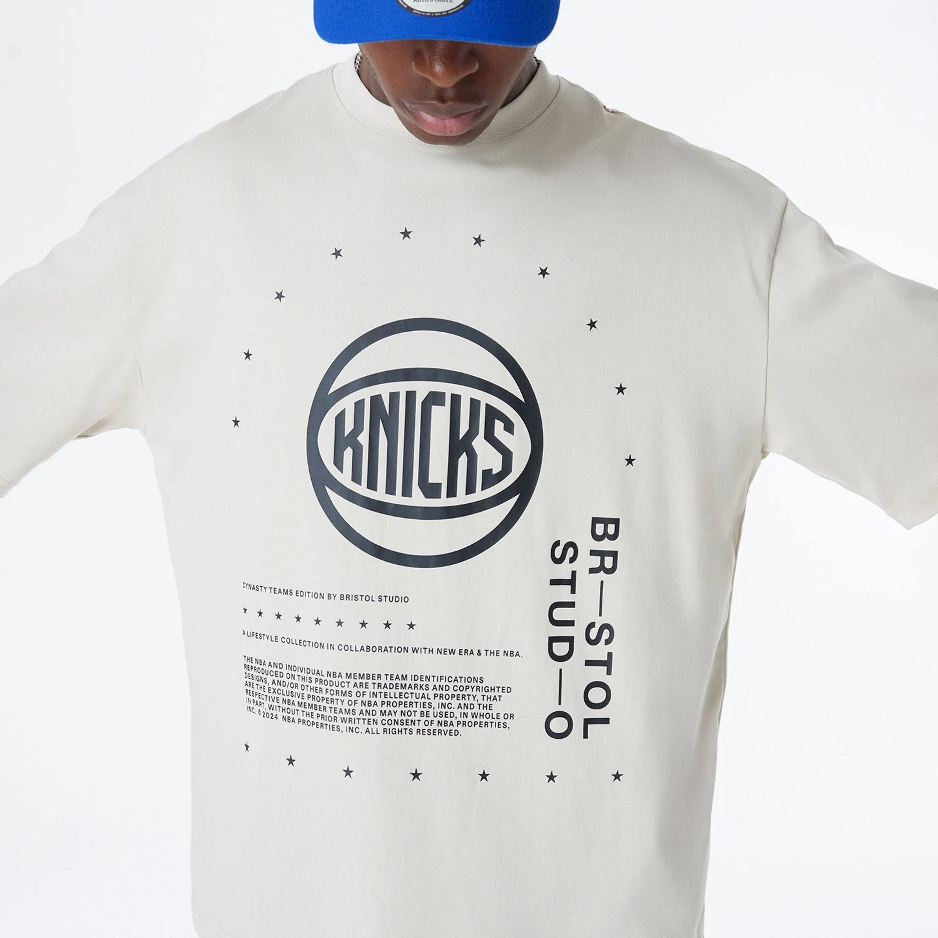 The Male model is wearing New York Knicks Bristol Studio x NBA Light Beige Oversized T-Shirt 6