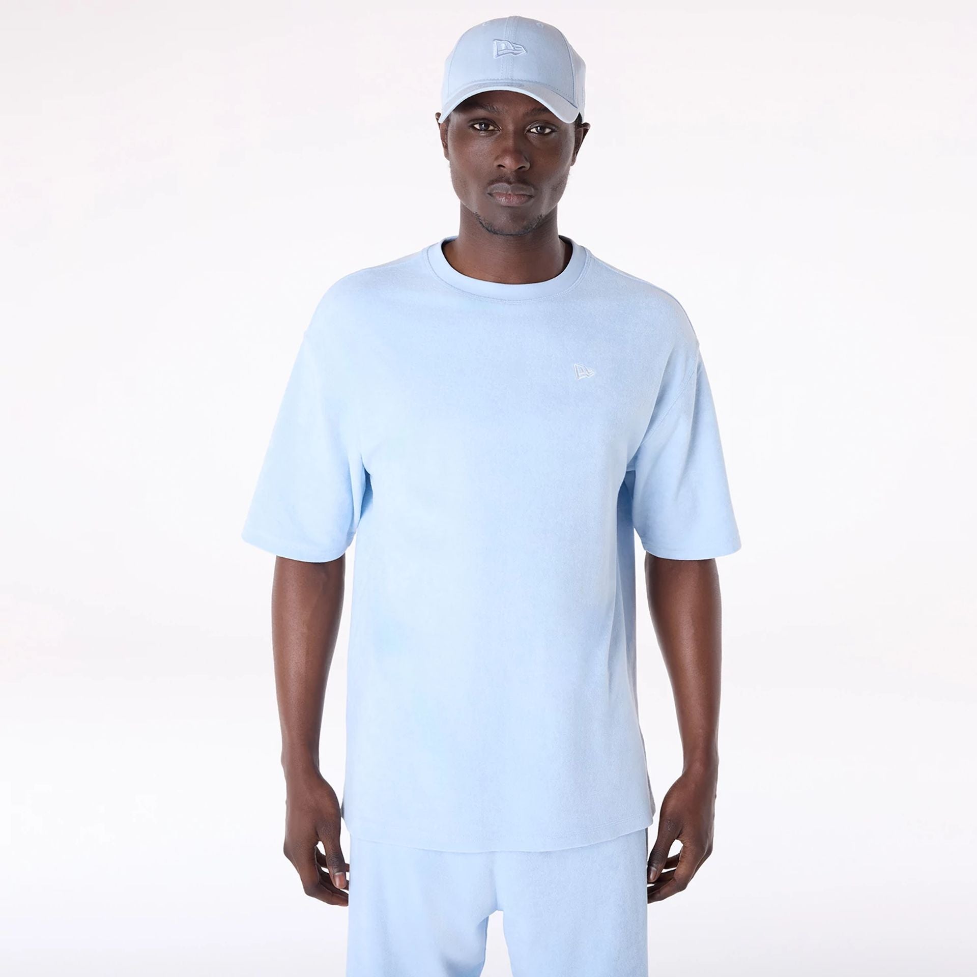 The Male model is wearing New Era Towelling Pastel Blue Oversized T-Shirt 1