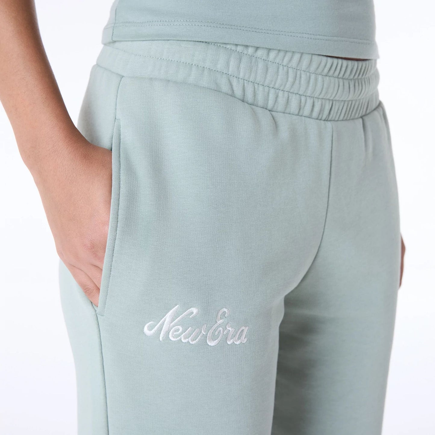 The Female model is wearing Womens New Era Script Pastel Green Joggers 3