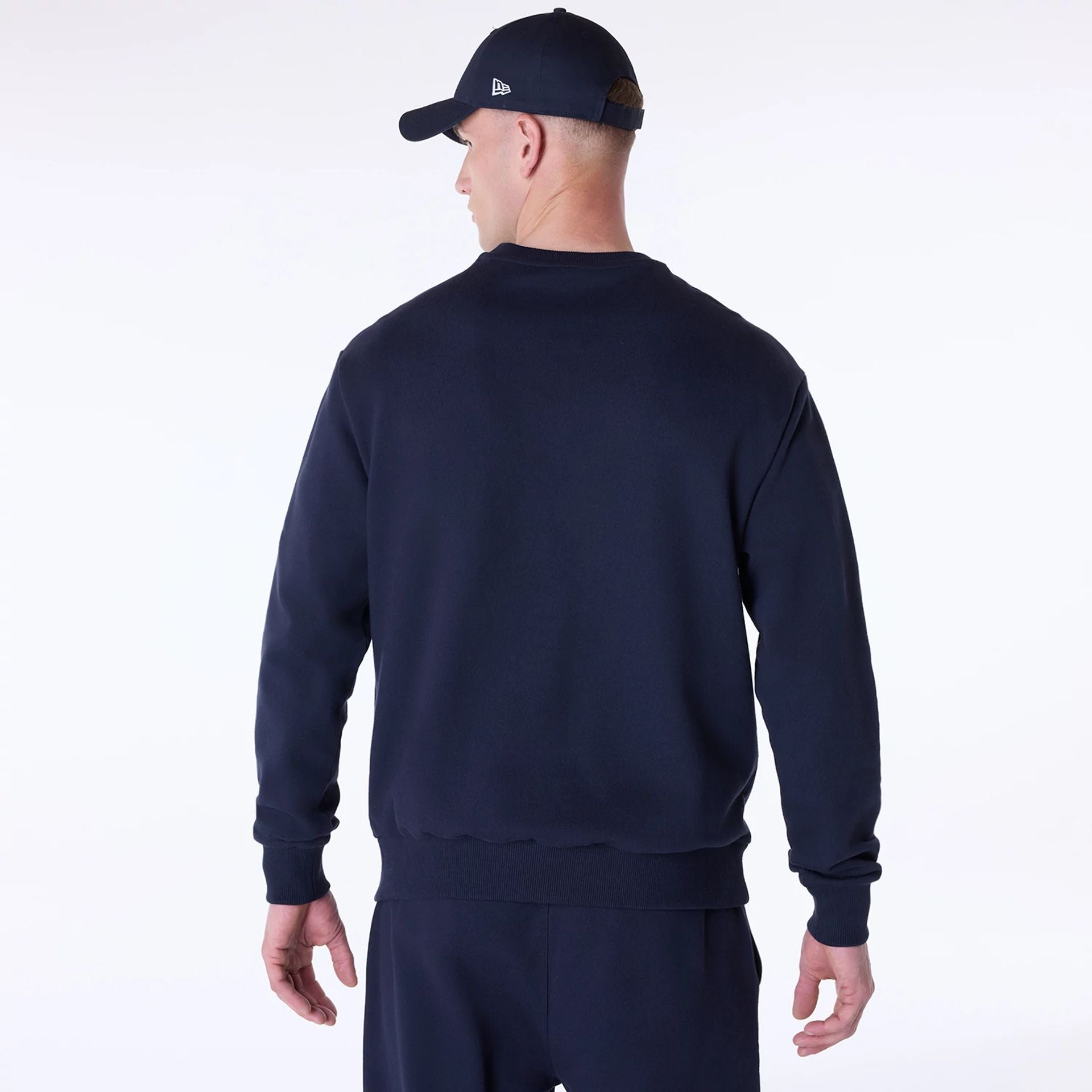 The Male model is wearing New Era Essential Navy Crew Neck Sweater 2