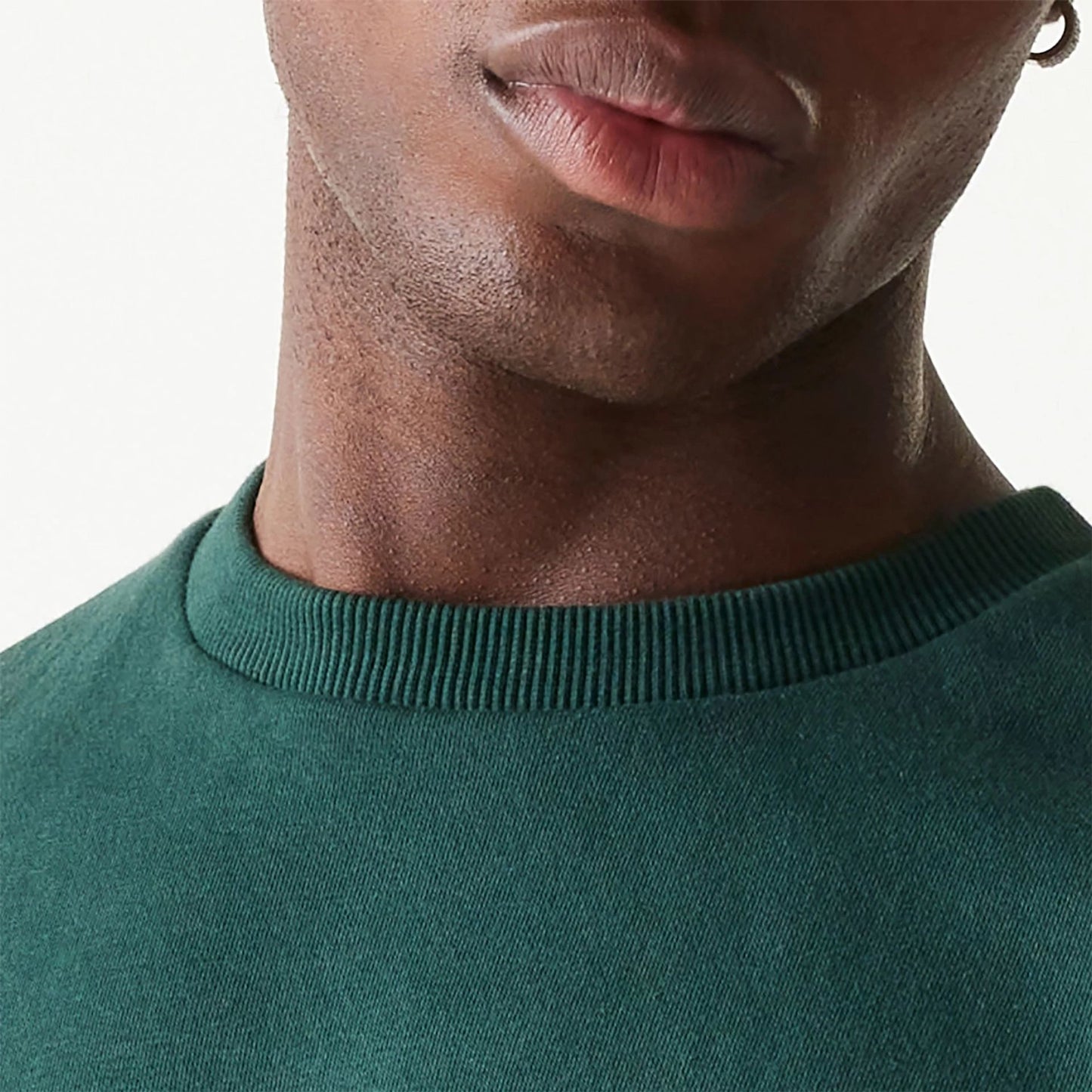 The Male model is wearing New Era Essential Brushed Fleece Dark Green Crewneck Sweater 6