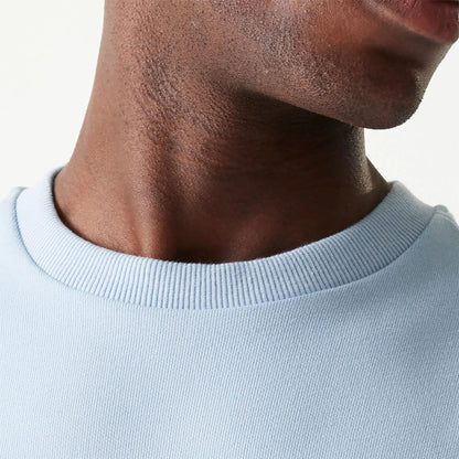 The Male model is wearing New Era Essential Pastel Blue Crewneck Sweater 6