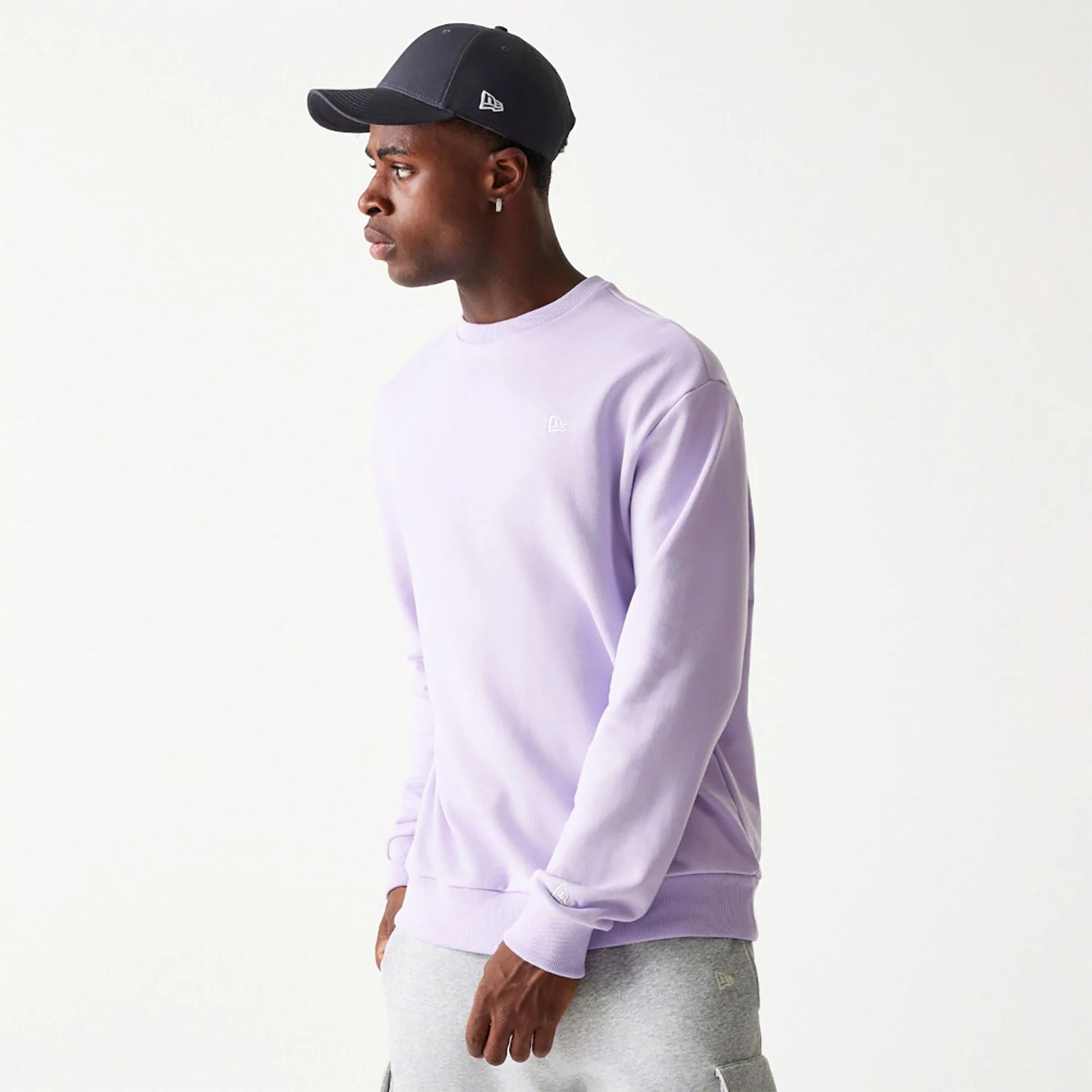 The Male model is wearing New Era Essential Pastel Purple Crewneck Sweater 1