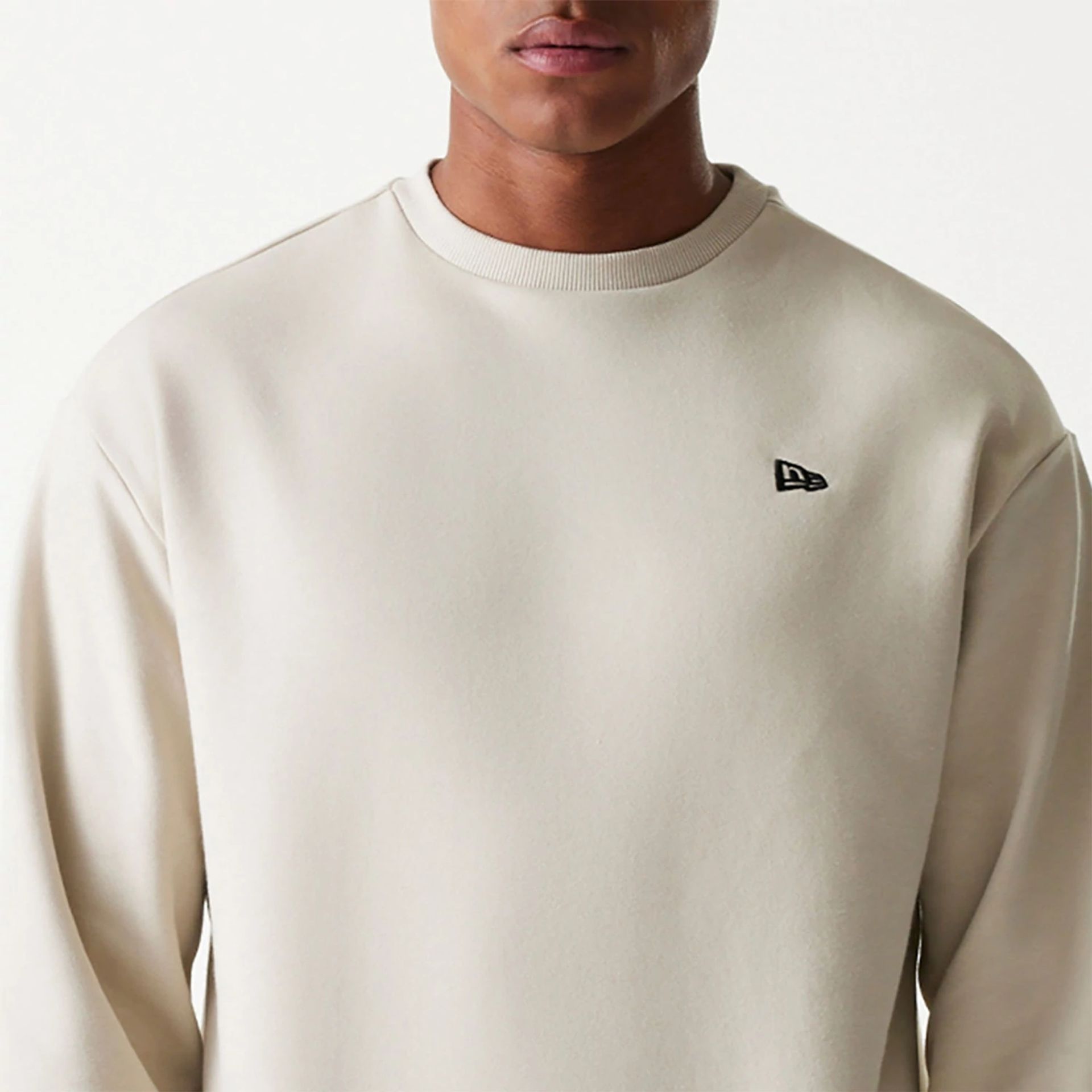 The Male model is wearing New Era Essential Brushed Fleece Light Beige Crewneck Sweater 3