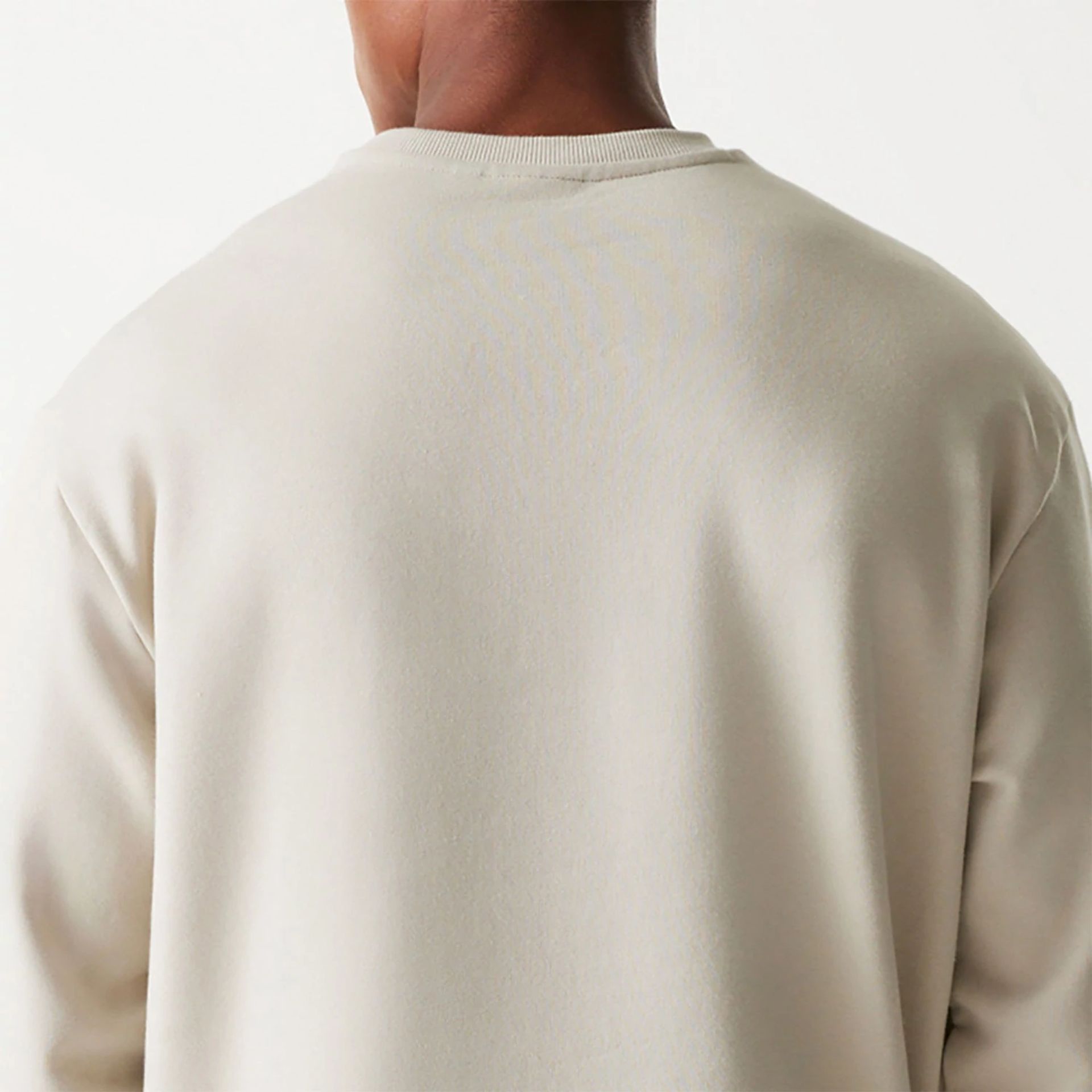 The Male model is wearing New Era Essential Brushed Fleece Light Beige Crewneck Sweater 7