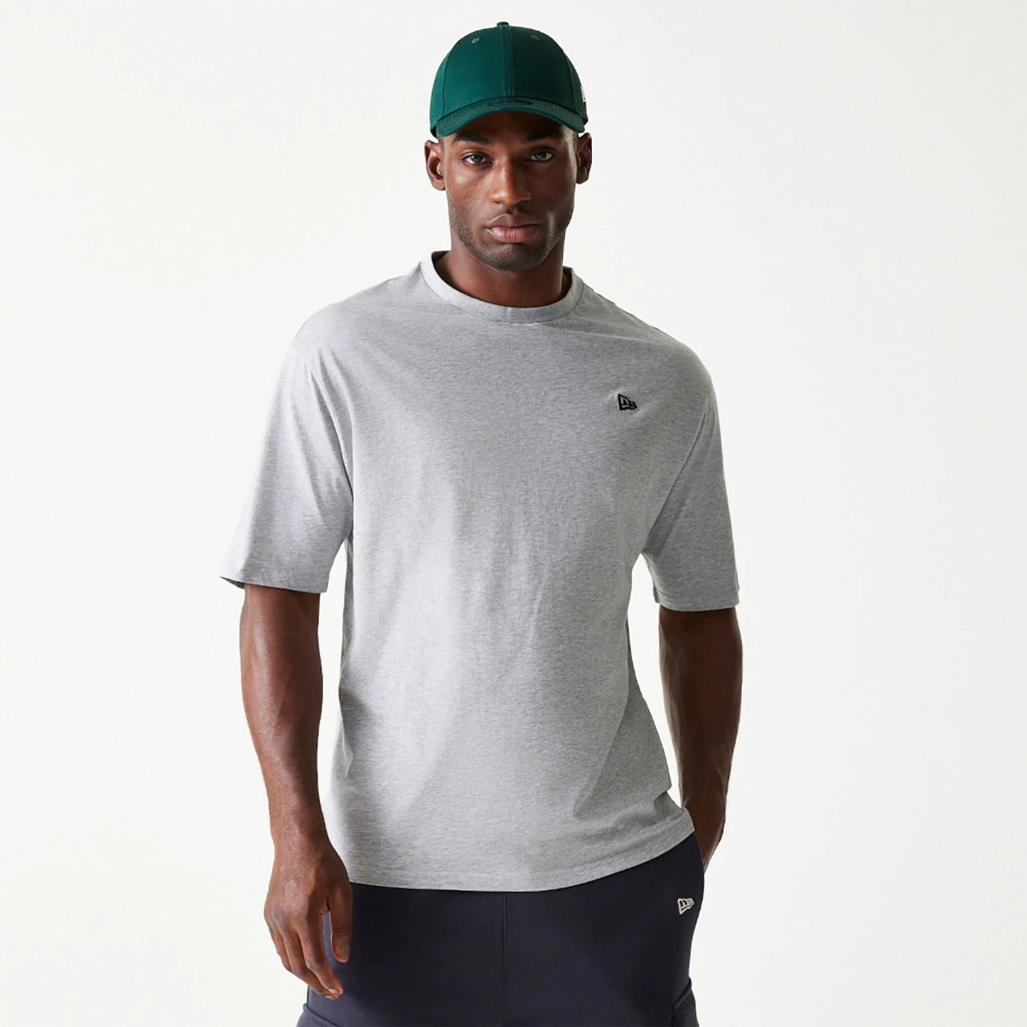 The Male model is wearing New Era Essential Grey Oversized T-Shirt 1