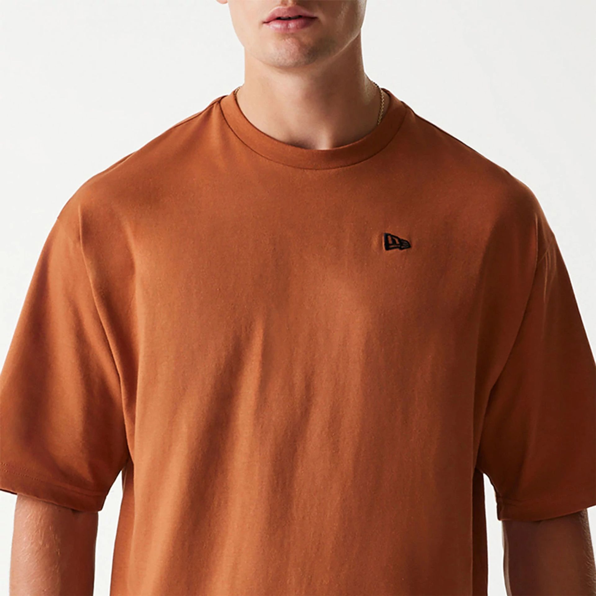 The Male model is wearing New Era Essential Brown Oversized T-Shirt 6