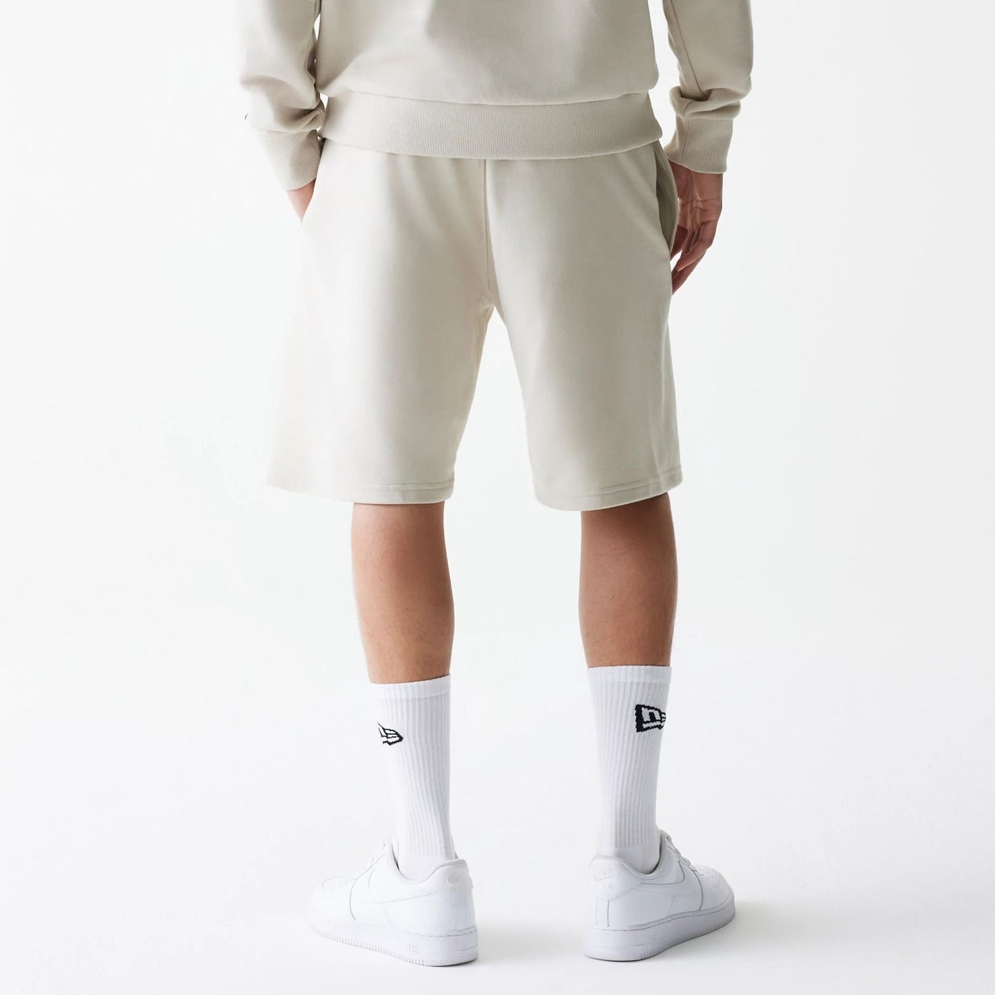 The Male model is wearing New Era Cream Oversized One Panel Shorts 2