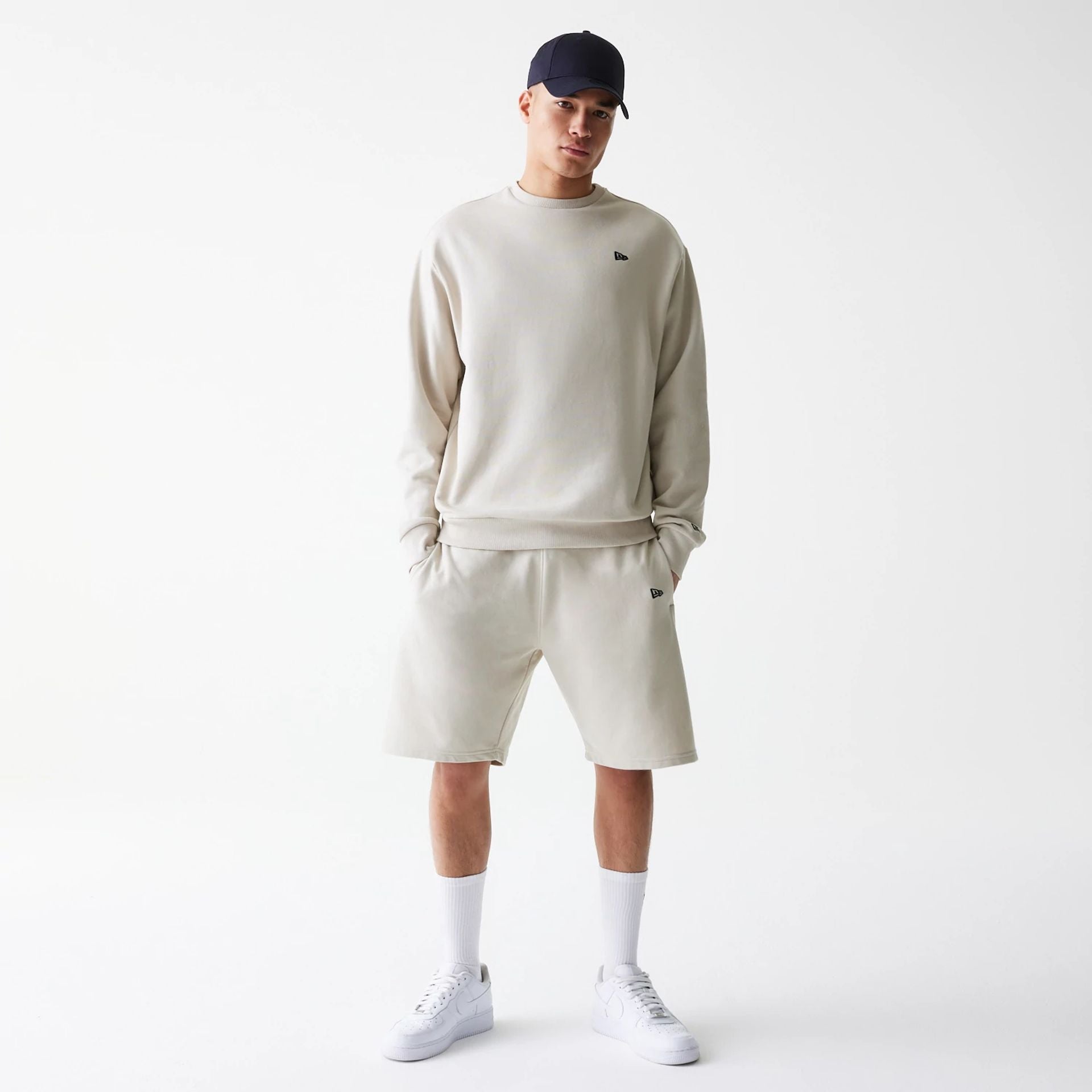 The Male model is wearing New Era Cream Oversized One Panel Shorts 8