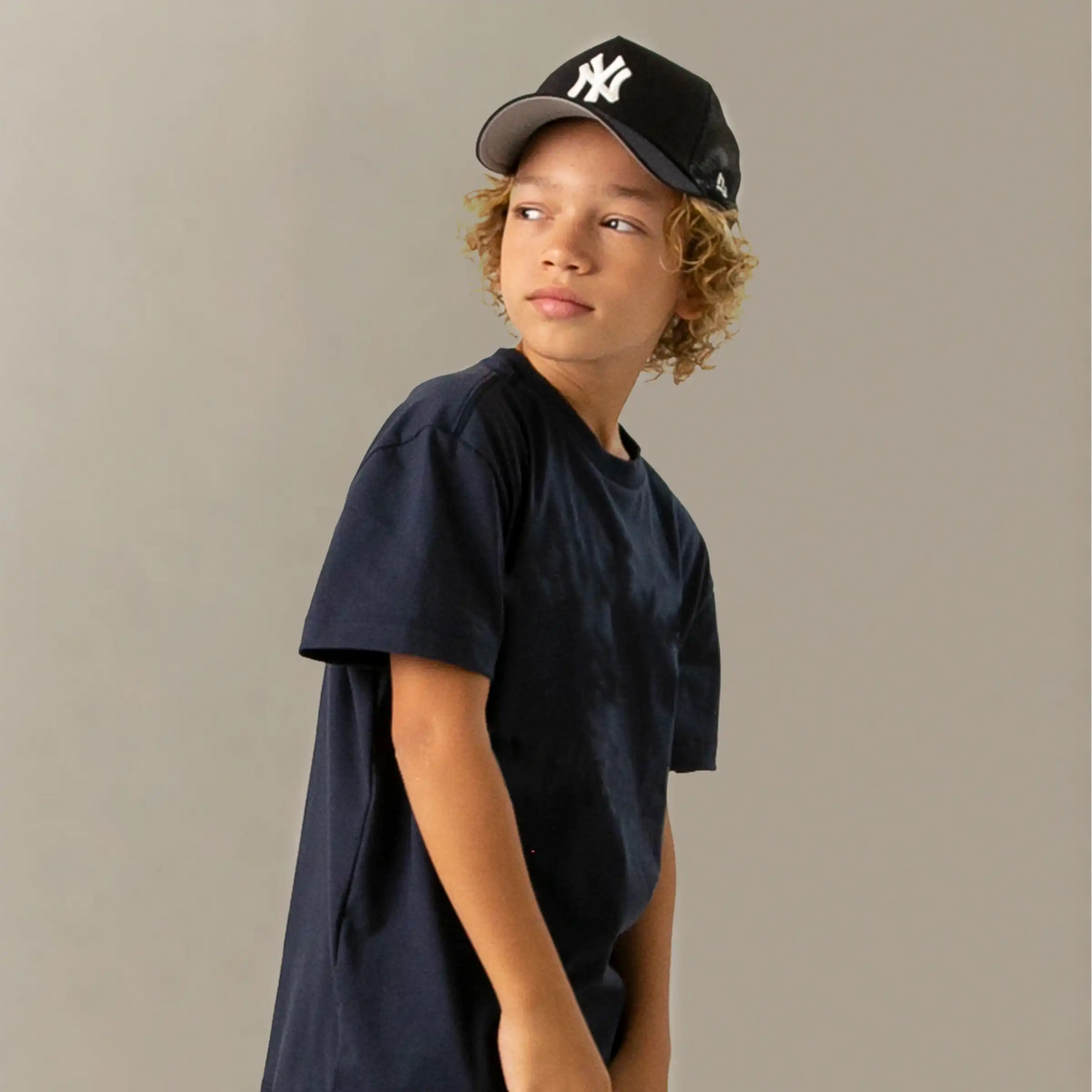 young boy wear a ny yankees cap with black top